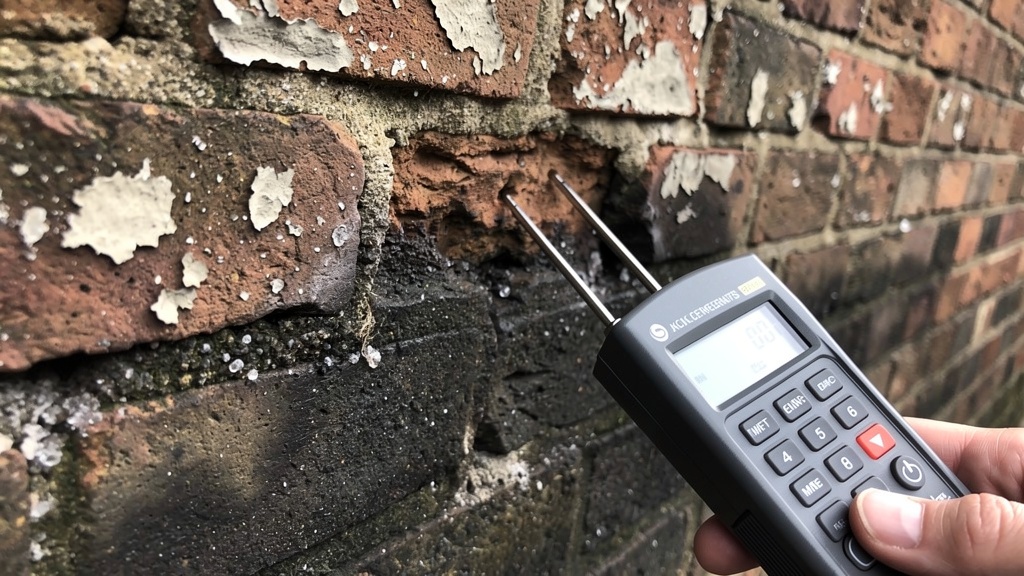 Surveyor measuring damp levels in a Victorian London property wall